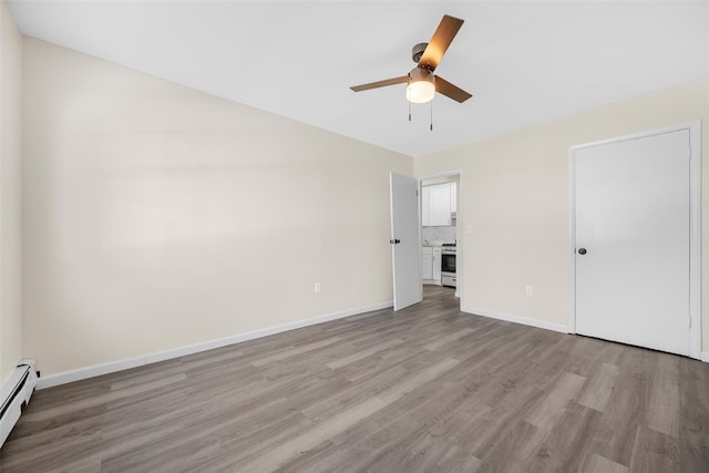 unfurnished bedroom featuring a baseboard heating unit, light wood-type flooring, baseboards, and a ceiling fan