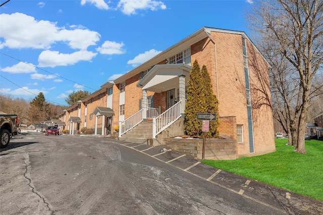 exterior space featuring a yard, a residential view, uncovered parking, and brick siding