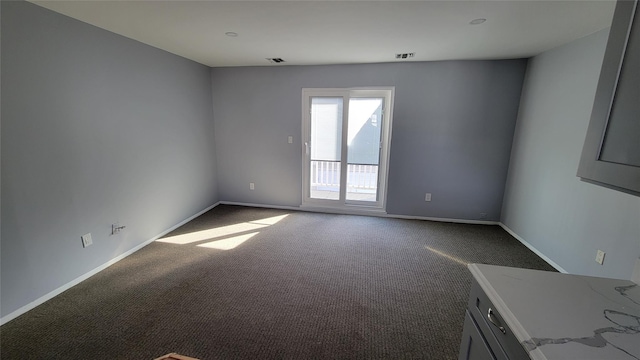 empty room featuring carpet, visible vents, and baseboards