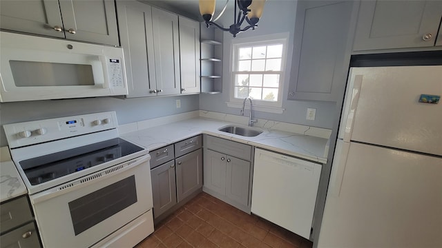 kitchen featuring white appliances, light stone counters, gray cabinetry, open shelves, and a sink