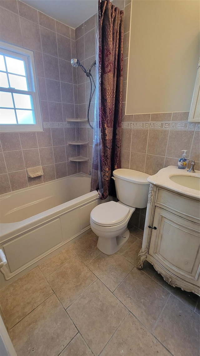 bathroom with toilet, shower / tub combo with curtain, tile patterned floors, vanity, and tile walls