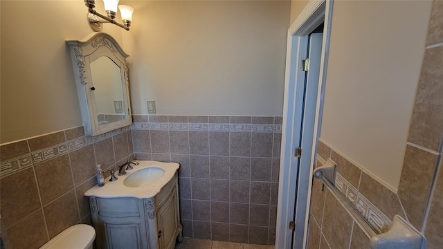 bathroom featuring toilet, wainscoting, tile walls, and vanity