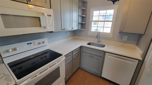 kitchen featuring white appliances, light stone countertops, gray cabinets, open shelves, and a sink