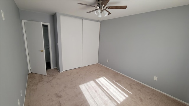 unfurnished bedroom with baseboards, a closet, a ceiling fan, and light colored carpet