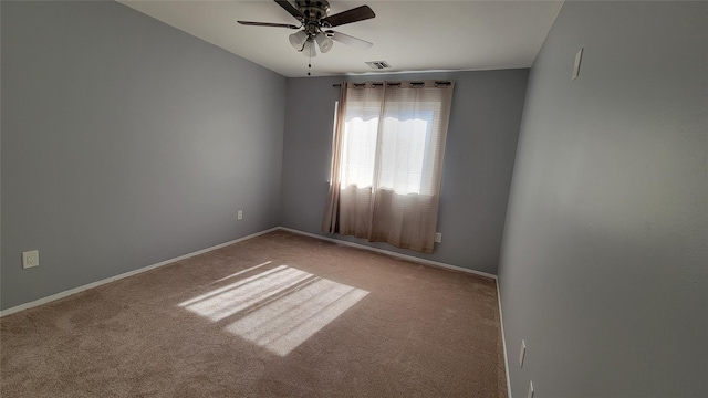 carpeted spare room featuring ceiling fan, visible vents, and baseboards