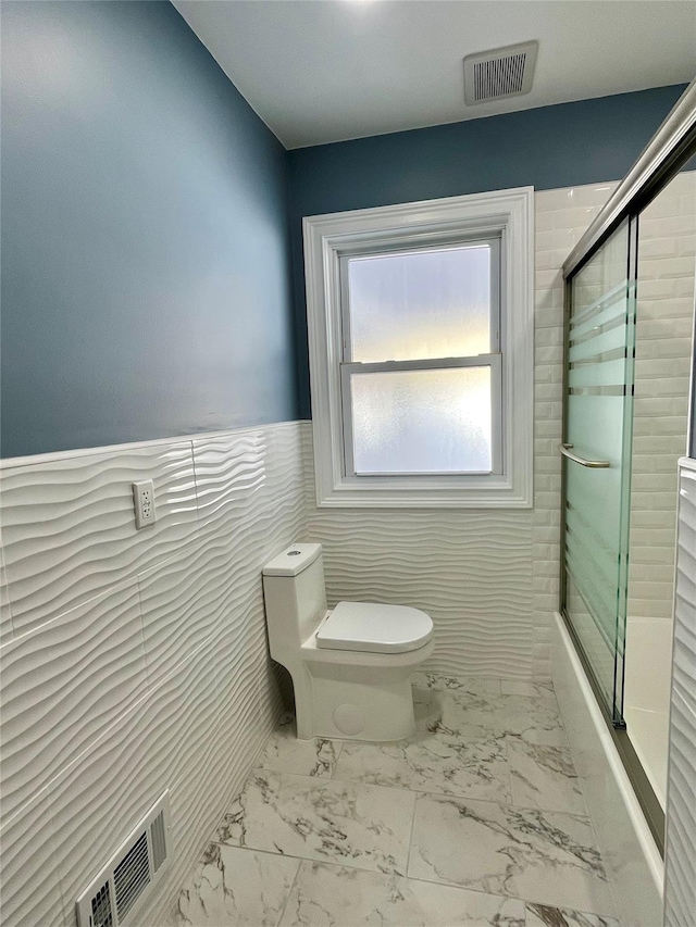 full bath featuring toilet, marble finish floor, visible vents, and a wainscoted wall