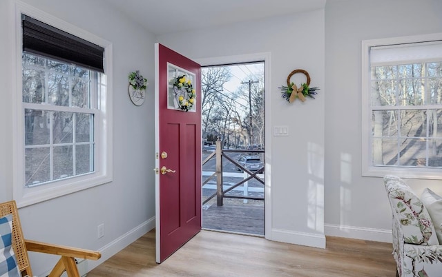 entryway featuring plenty of natural light, light wood-style floors, and baseboards