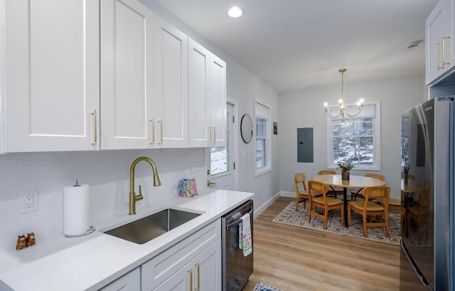 kitchen with white cabinets, light countertops, decorative light fixtures, appliances with stainless steel finishes, and a sink