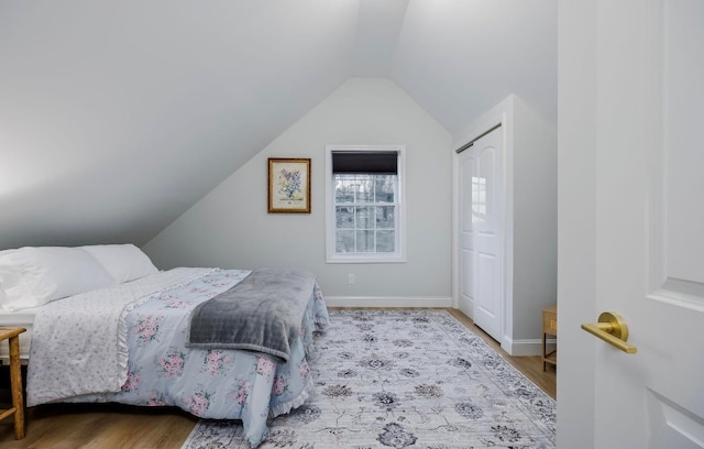 bedroom featuring vaulted ceiling, light wood-style floors, and baseboards