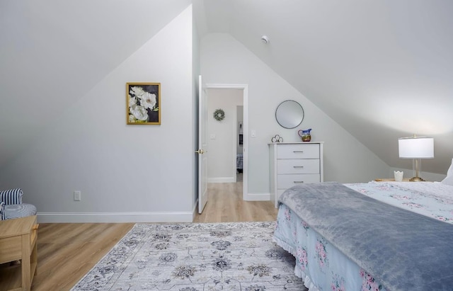 bedroom with lofted ceiling, light wood finished floors, and baseboards