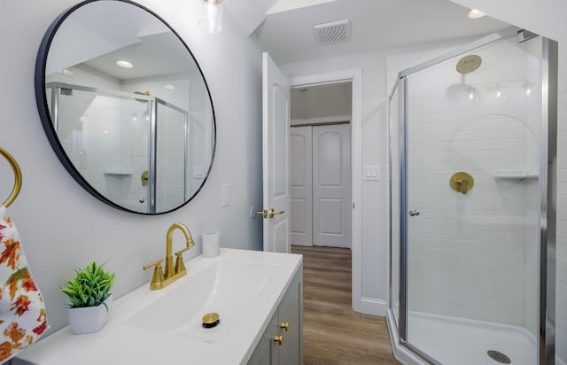 full bath featuring a shower stall, vanity, wood finished floors, and visible vents