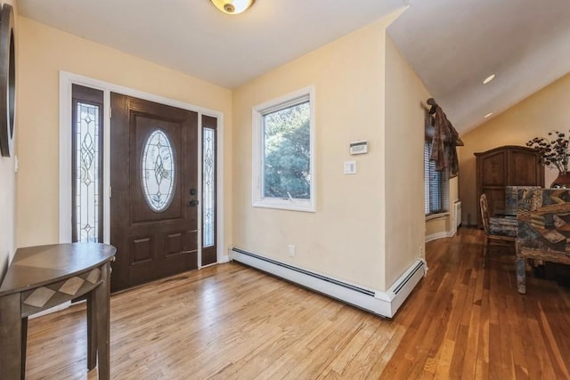 entryway with light wood-style floors, a baseboard radiator, and vaulted ceiling