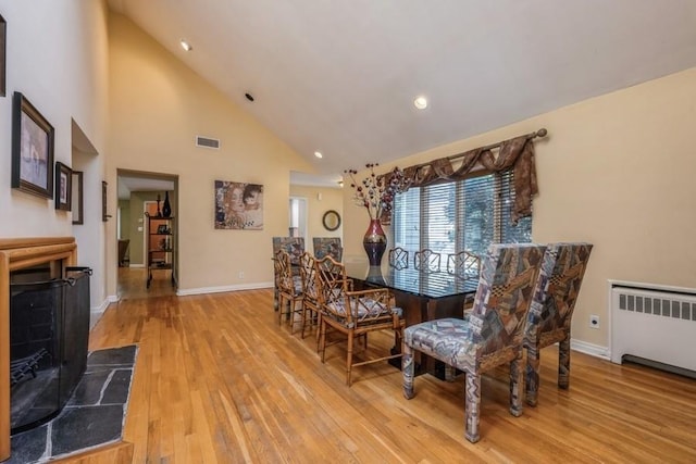 dining area with baseboards, wood finished floors, visible vents, and radiator