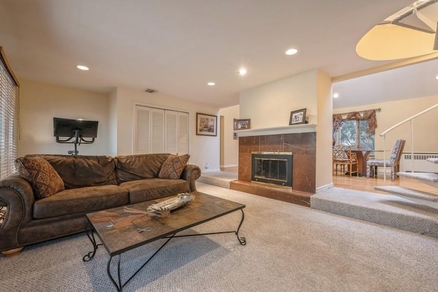 carpeted living room featuring radiator heating unit, a tiled fireplace, visible vents, and recessed lighting