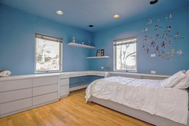 bedroom with a baseboard heating unit, light wood-style flooring, and recessed lighting