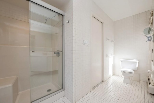 bathroom with a shower stall, tile walls, toilet, and tile patterned floors