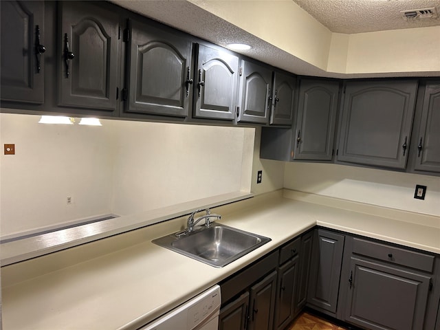 kitchen with a textured ceiling, visible vents, light countertops, and a sink