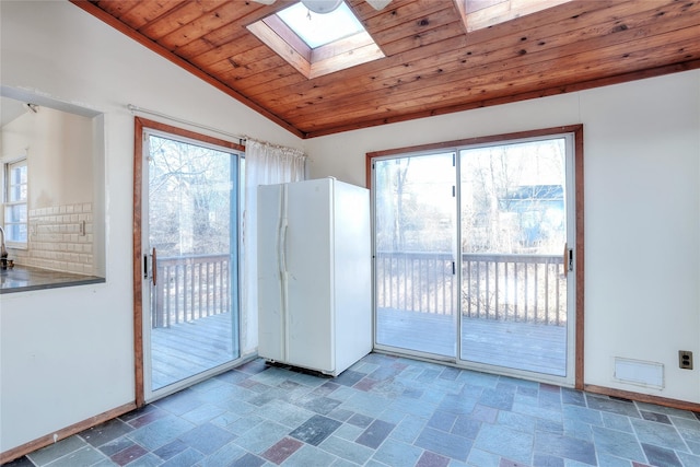 doorway to outside with lofted ceiling with skylight, wood ceiling, baseboards, and stone tile flooring