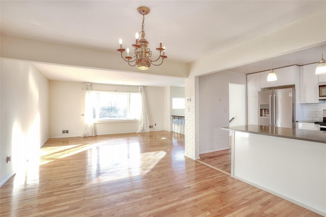 kitchen featuring appliances with stainless steel finishes, light wood-style floors, white cabinets, and hanging light fixtures