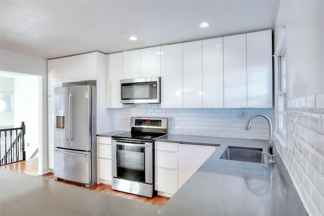 kitchen with appliances with stainless steel finishes, modern cabinets, a sink, and white cabinets