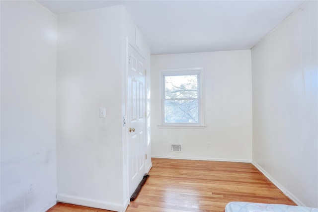 unfurnished room featuring light wood-type flooring, visible vents, and baseboards