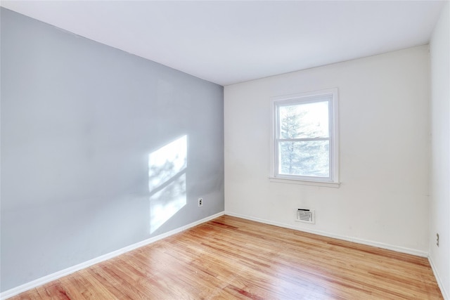 empty room featuring light wood-style floors, visible vents, and baseboards