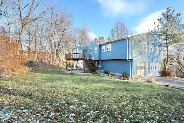 rear view of property with a lawn, stairway, a garage, driveway, and a wooden deck