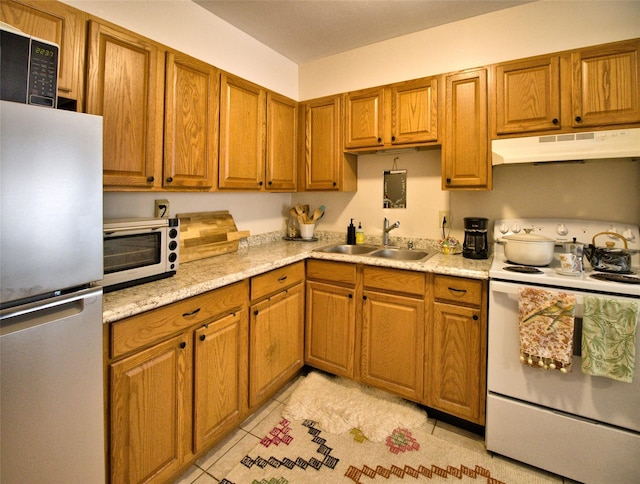 kitchen with freestanding refrigerator, a sink, light countertops, under cabinet range hood, and white range with electric stovetop