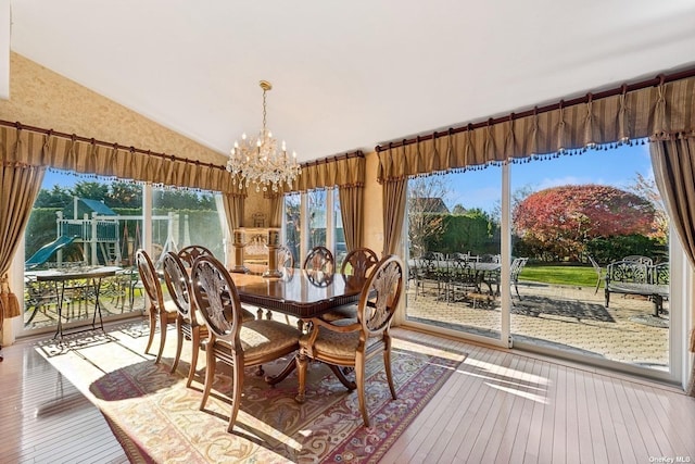 dining room with a chandelier, lofted ceiling, and wood finished floors