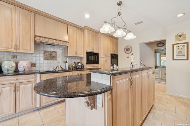 kitchen with light brown cabinetry, a center island, black appliances, dark stone countertops, and decorative light fixtures