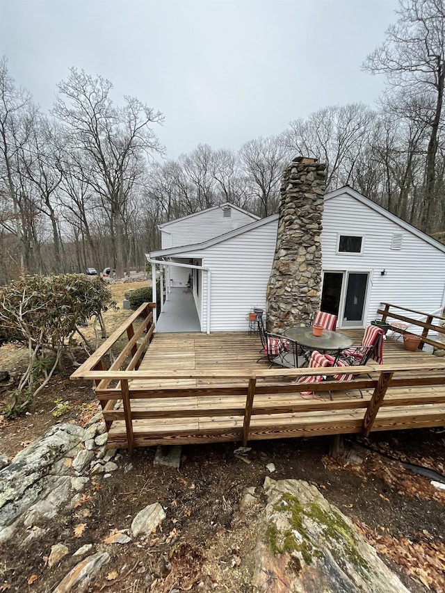 back of house featuring a wooden deck and a chimney