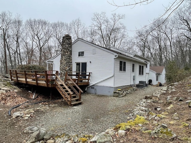 rear view of house with stairway, central AC unit, a chimney, and a wooden deck