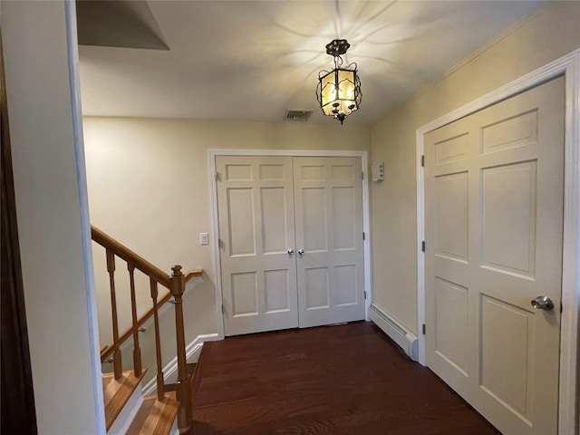 interior space featuring visible vents, dark wood-style flooring, a baseboard radiator, baseboards, and stairs