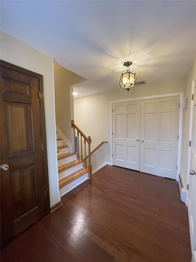 foyer entrance featuring dark wood-style floors, stairway, an inviting chandelier, and baseboards