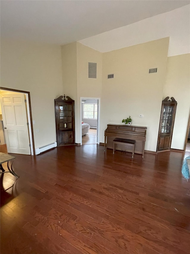 unfurnished living room featuring visible vents, baseboard heating, and wood finished floors