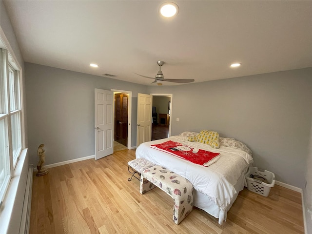 bedroom featuring baseboards, a baseboard heating unit, and light wood-style floors