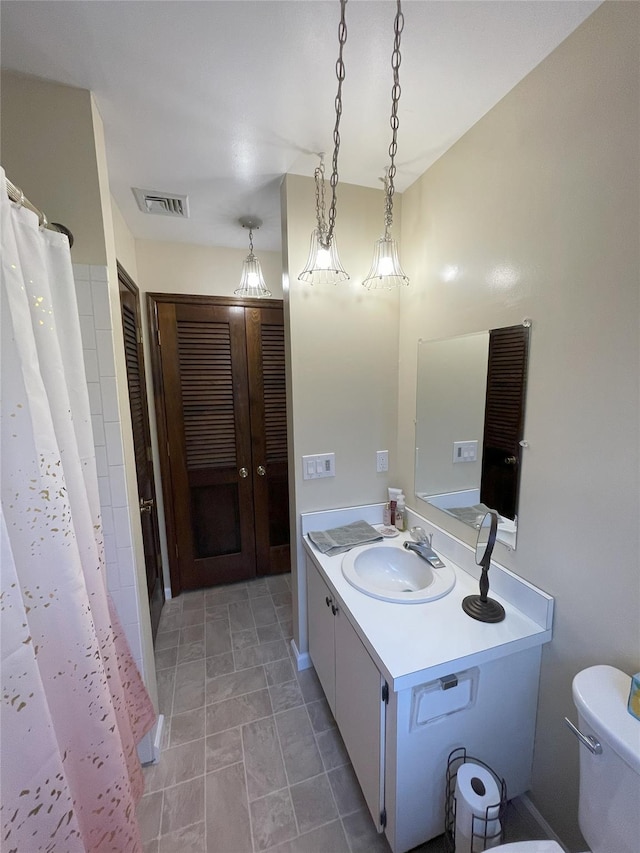 full bath featuring vanity, curtained shower, toilet, and visible vents