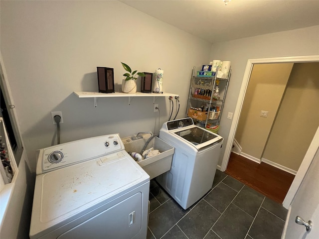 laundry area with baseboards, dark tile patterned floors, washing machine and dryer, laundry area, and a sink