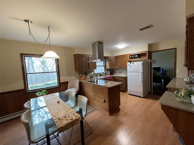 kitchen featuring a wainscoted wall, visible vents, freestanding refrigerator, a sink, and island range hood