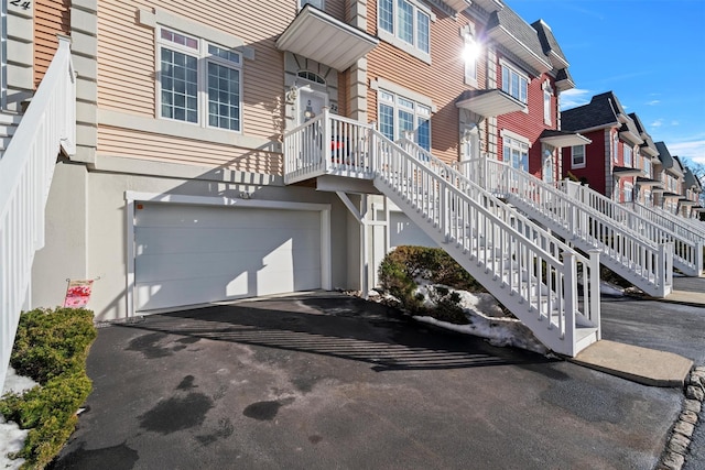 exterior space featuring a garage, a residential view, and aphalt driveway