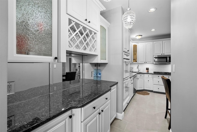 kitchen featuring hanging light fixtures, stainless steel microwave, white cabinetry, and recessed lighting