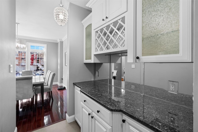 kitchen with a chandelier, white cabinets, glass insert cabinets, and ornamental molding