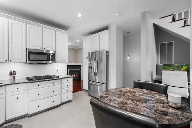 kitchen featuring recessed lighting, stainless steel appliances, white cabinetry, dark stone counters, and tasteful backsplash