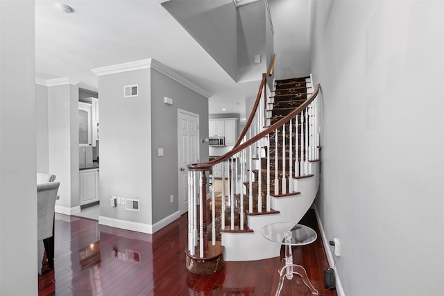 stairway featuring ornamental molding, wood-type flooring, visible vents, and baseboards