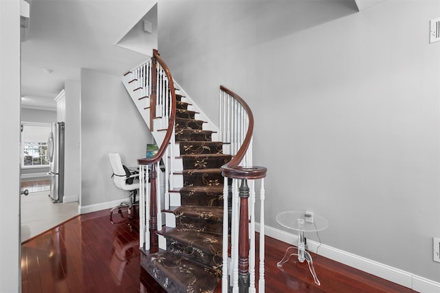 stairs featuring crown molding, baseboards, and wood finished floors