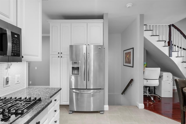 kitchen featuring light tile patterned flooring, stainless steel appliances, white cabinetry, decorative backsplash, and dark stone countertops