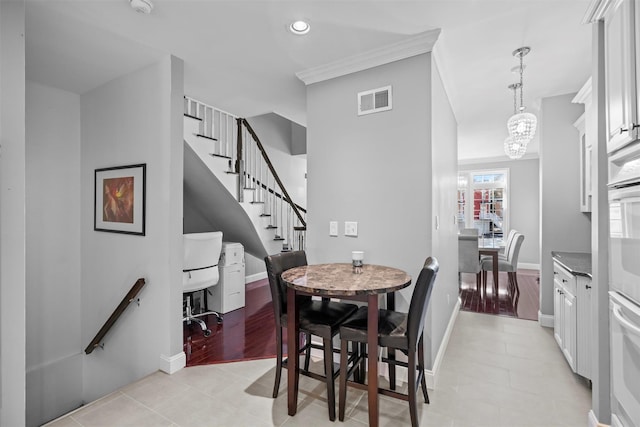 dining area featuring light tile patterned flooring, a notable chandelier, visible vents, baseboards, and stairs