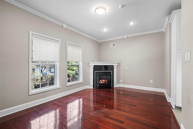 unfurnished living room featuring baseboards, visible vents, a glass covered fireplace, wood finished floors, and crown molding