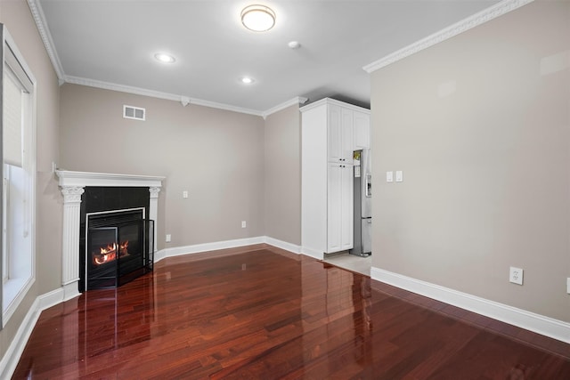 unfurnished living room with visible vents, baseboards, a glass covered fireplace, wood finished floors, and crown molding