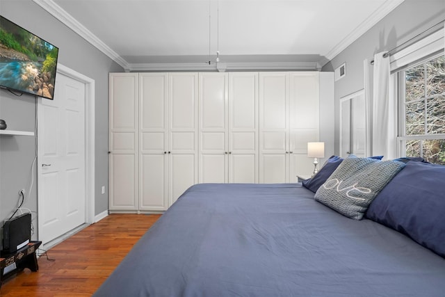 bedroom with ornamental molding, wood finished floors, and visible vents